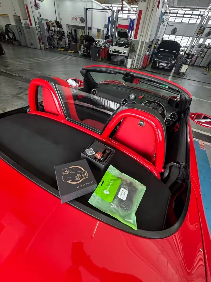 Dashcam Sentinelle One et son coffret posés sur un cabriolet sportif rouge